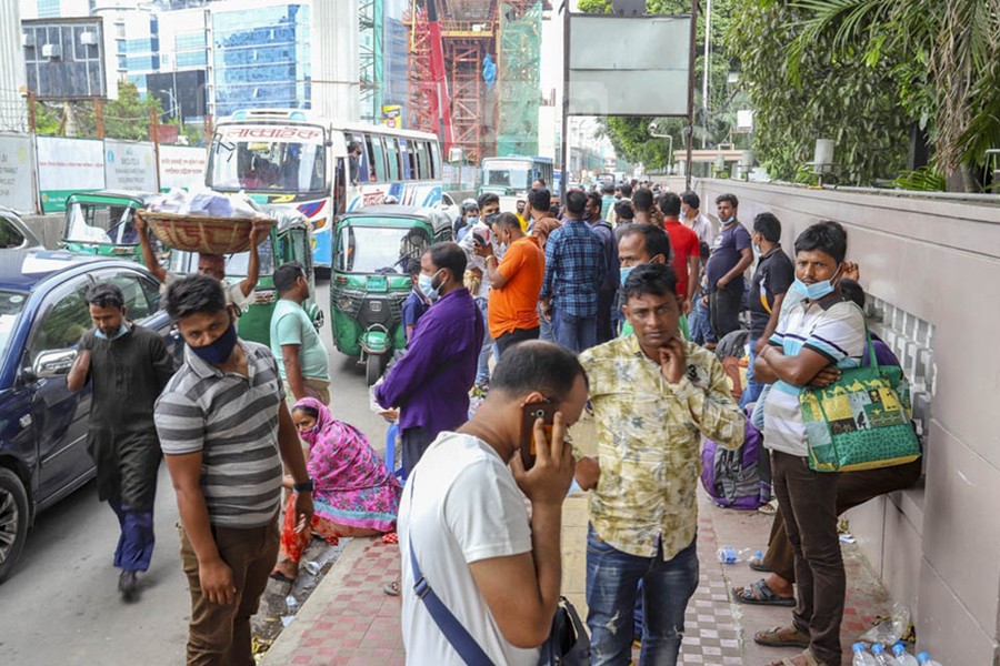 Bangladeshi migrant workers, who have been stranded due to COVID-19 restrictions, wait outside the Saudia office in Dhaka’s Karwan Bazar for air tickets to Saudi Arabia