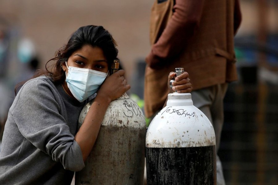 A woman holds on to the oxygen cylinders for a patient after refiling them at a factory, amidst the spread of coronavirus disease (Covid-19) surge as India's outbreak spreads across South Asia, in Kathmandu, Nepal on May 9, 2021 — Reuters/Files