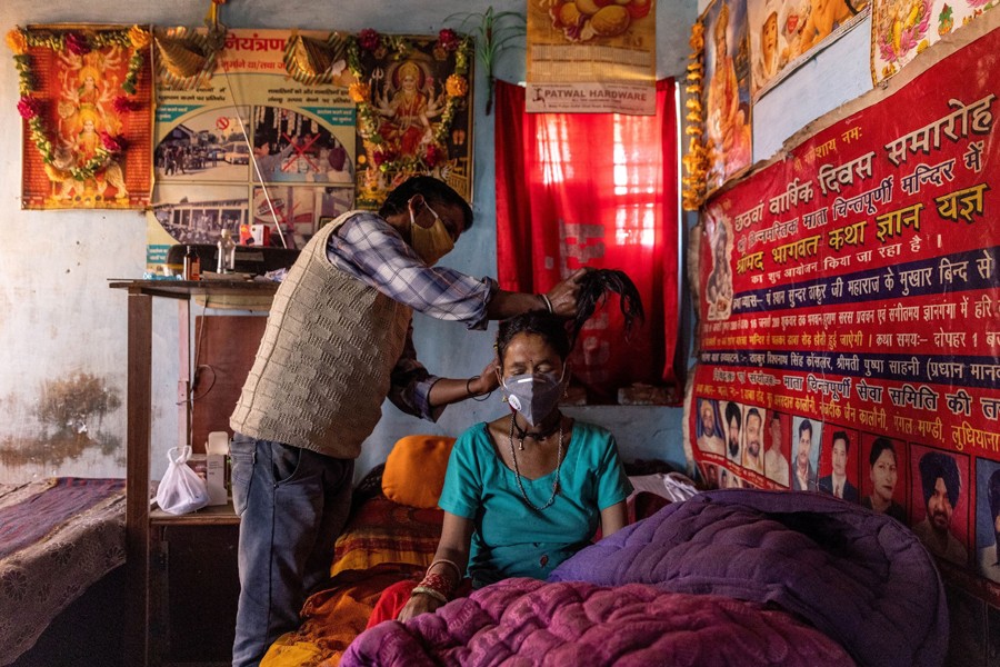 Man ties up the hair of his wife who is suffering from the coronavirus disease (Covid-19), before taking her to a local government dispensary, at their home in Kaljikhal, in the northern state of Uttarakhand, India on May 23, 2021 — Reuters/Files