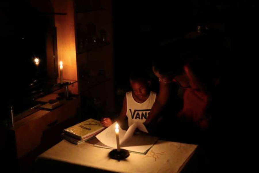 Nokuthula Thwala helps her nephew, Ayanda, with school work while using a candle during load shedding in Soweto, South Africa on February 2, 2020 — Reuters/Files