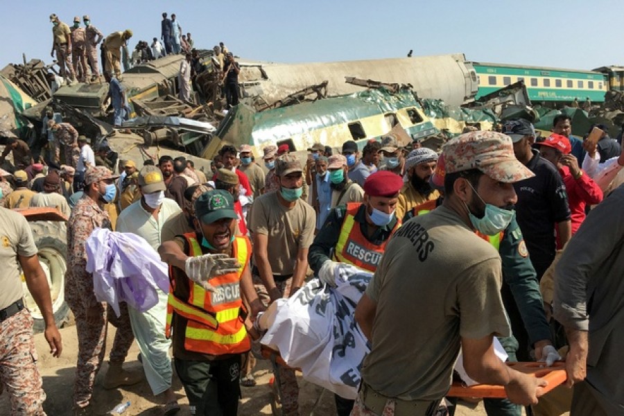 Paramilitary soldiers and rescue workers move a body of a man from the site following a collision between two trains in Ghotki, Pakistan Jun 7, 2021. REUTERS