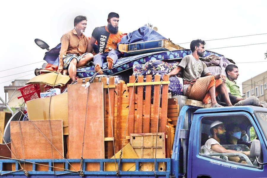 With 'strict' lockdown coming into force this week, a family with their belongings loaded onto a truck leaving Dhaka city for their village home on Saturday. The photo was taken in Khilgaon area — FE photo by KAZ Sumon