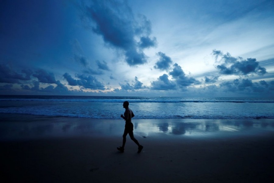 A man jogs in Karon beach as Phuket gets ready to open to overseas tourists from July 1, allowing fully vaccinated foreigns to visit the resort island without quarantine, in Phuket, Thailand Jun 30, 2021. REUTERS