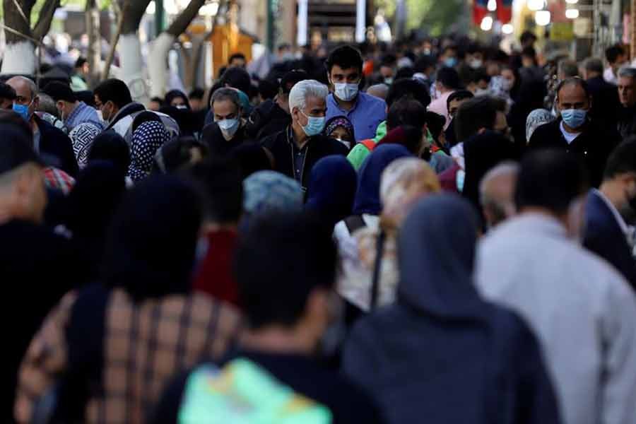 Iranians wearing protective face masks against the coronavirus walk in a crowded area of the capital Tehran on March 30 this year -Reuters file photo