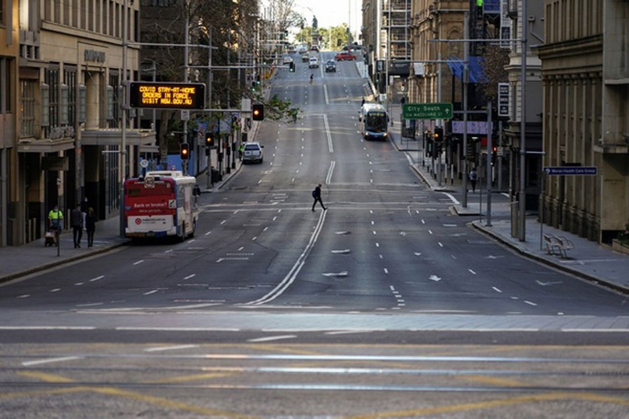 A pedestrian crosses an unusually quiet street in the city centre during a lockdown to curb the spread of the coronavirus disease (COVID-19) in Sydney, Australia, July 5, 2021. REUTERS