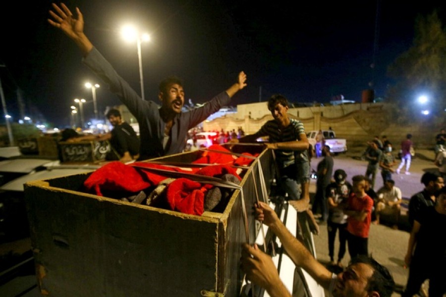 People react next to the body of a casualty outside al-Hussain coronavirus hospital after a fire, in Nassiriya, Iraq, July 13, 2021 - Reuters