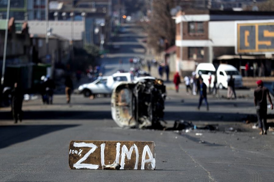 The remains of a burnt car and a sign block the road after stick-wielding protesters marched through the streets, as violence following the jailing of former South African President Jacob Zuma spread to the country's main economic hub in Johannesburg, South Africa on July 11, 2021 — Reuters photo