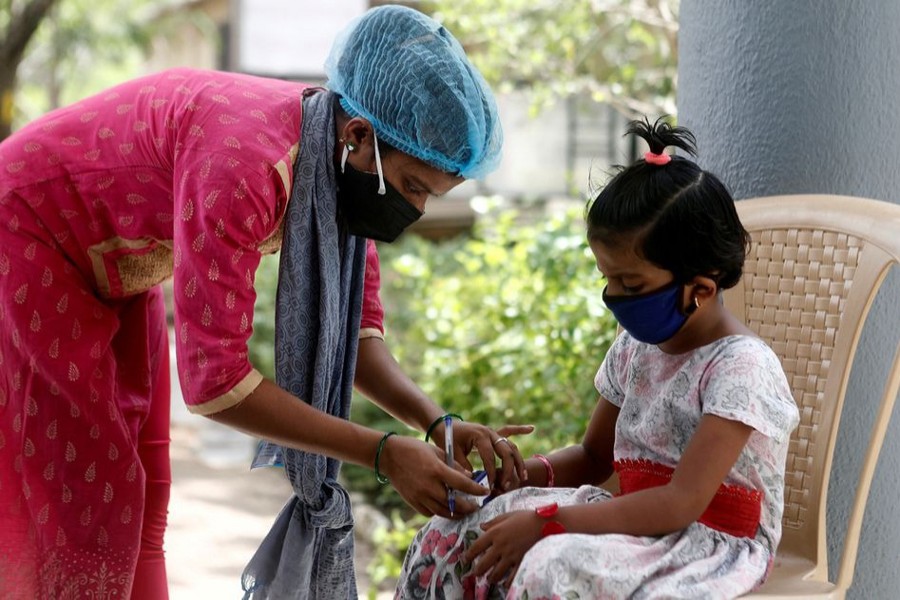 A nurse checks a coronavirus disease patient's pulse before she is admitted into a school turned Covid-19 care facility on the outskirts of Mumbai, India on May 24, 2021 — Reuters/Files