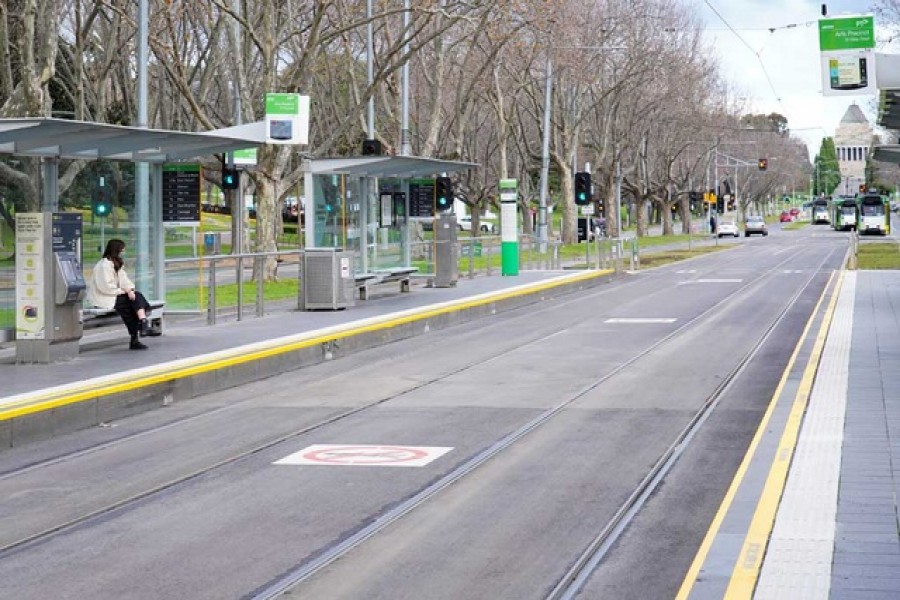 A lone passenger sits at a tram stop on a mostly-empty city centre street on the first day of a lockdown as the state of Victoria looks to curb the spread of a coronavirus disease (COVID-19) outbreak in Melbourne, Australia, July 16, 2021. REUTERS