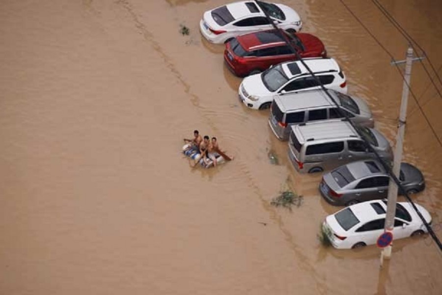 People on a makeshift raft make their way through a flooded road following heavy rainfall in Zhengzhou, Henan province, China July 22, 2021. REUTERS/Aly Song