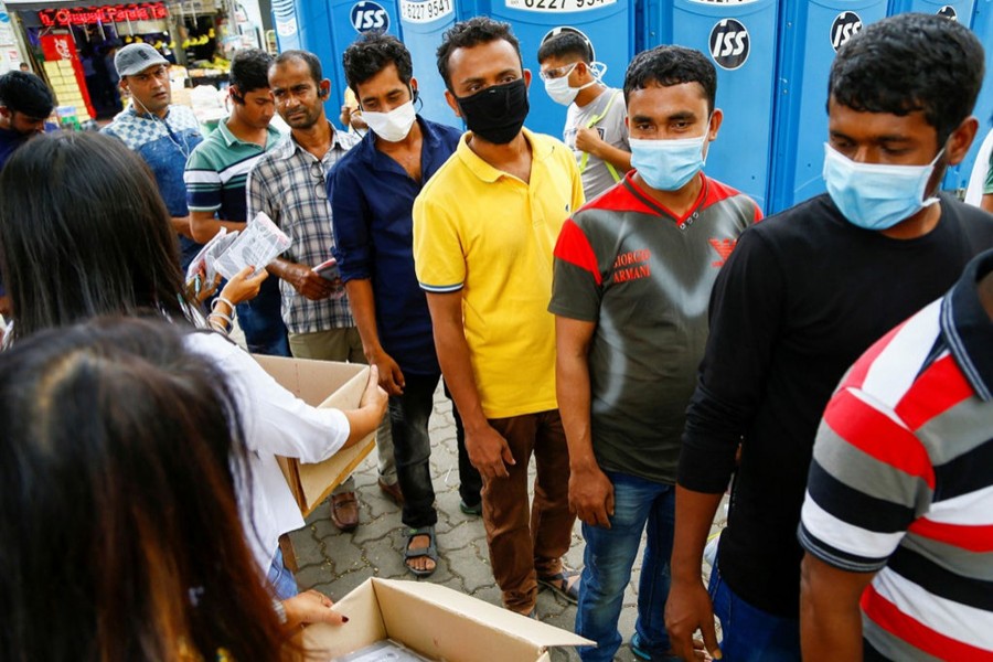 Migrant workers, mostly from Bangladesh, line up to collect free masks and have their temperatures taken in Singapore in February last year — Reuters/Files