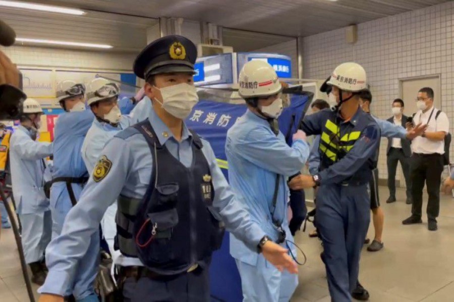 Police escort rescue workers carrying a person through a train station after a knife attack on a train in Tokyo, Japan August 6, 2021 in this still image taken from video obtained by REUTERS