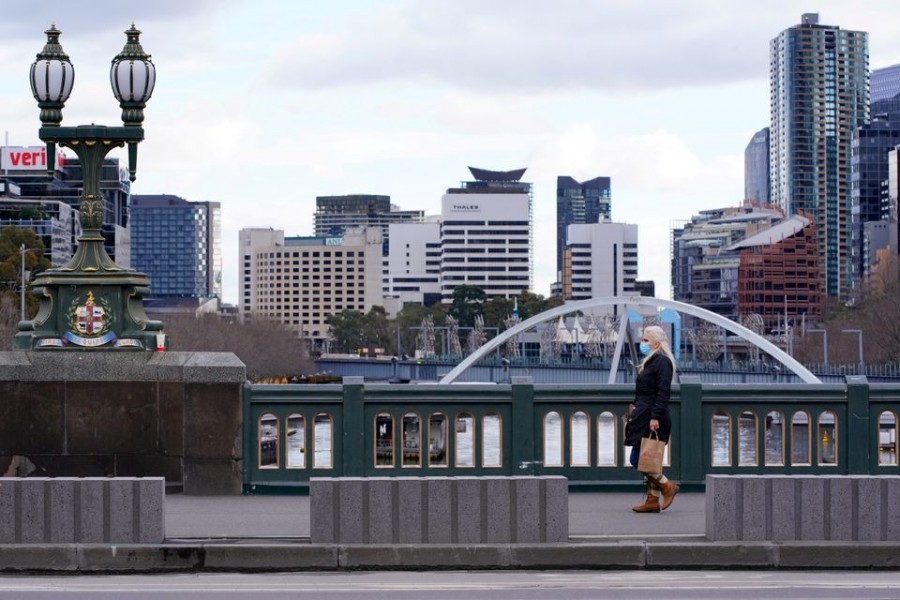 A lone woman, wearing a protective face mask, walks across an unusually quiet city centre bridge as the state of Victoria looks to curb the spread of a coronavirus disease (Covid-19) outbreak in Melbourne, Australia on July 16, 2021 — Reuters/Files