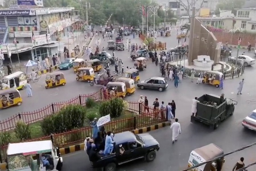 Taliban militants waving a Taliban flag on the back of a pickup truck drive past a crowded street at Pashtunistan Square area in Jalalabad, Afghanistan, on Aug 15, 2021. Social media website/via REUTERS