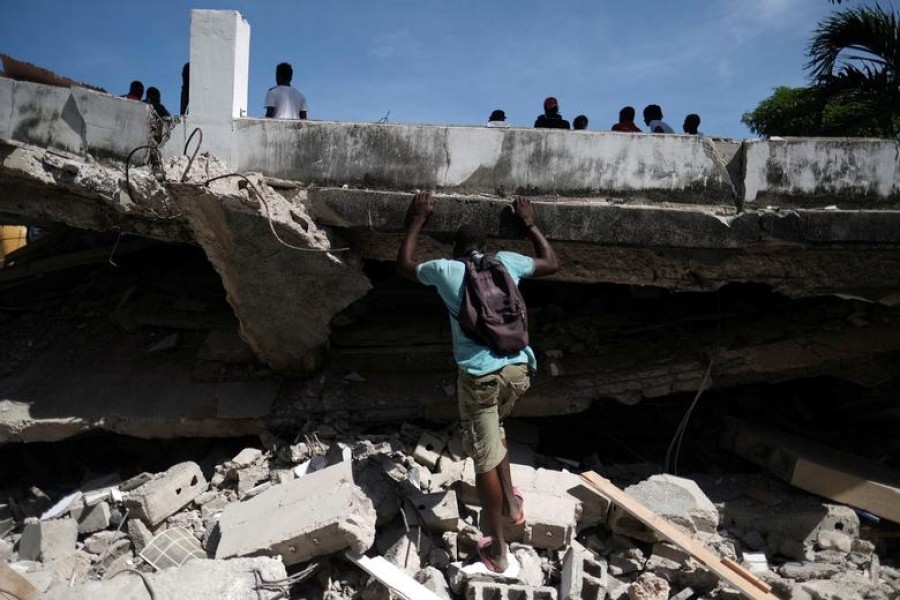 A man searches the site of a collapsed hotel in Les Cayes, Haiti on August 16, 2021 — Retuers photo