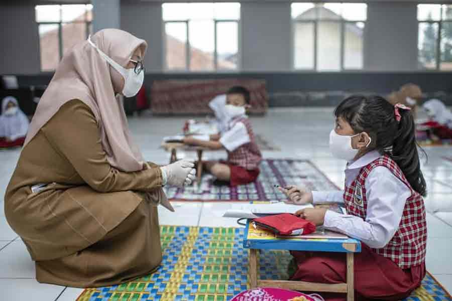 Nayla, 7, a student in a primary school, asks her teacher a question during class at the local village hall in Bandung, West Java province, Indonesia. -UNICEF photo