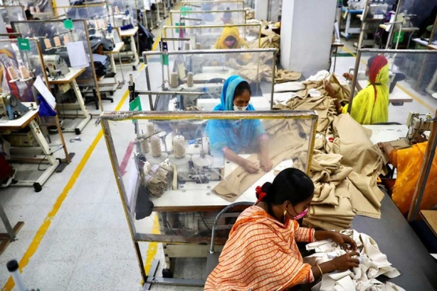 Employees work between polythene sheets, as a safety measure to reduce the spread of coronavirus disease (COVID-19), at The Civil Engineering Limited garment factory in Dhaka, Bangladesh, August 17, 2021. Reuters