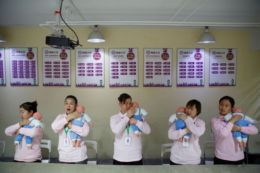 Students at Ayi University, a training programme for domestic helpers, practice on baby dolls during a course teaching childcare in Beijing, China, December 5, 2018 — Reuters/Thomas Peter