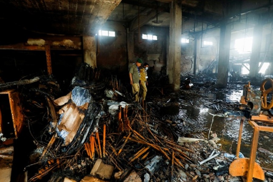 Members of the scout emergency response team, survey amid the burned wreckage, after a fire broke out at a multi-story chemical factory, in Karachi, Pakistan, August 27, 2021. Reuters