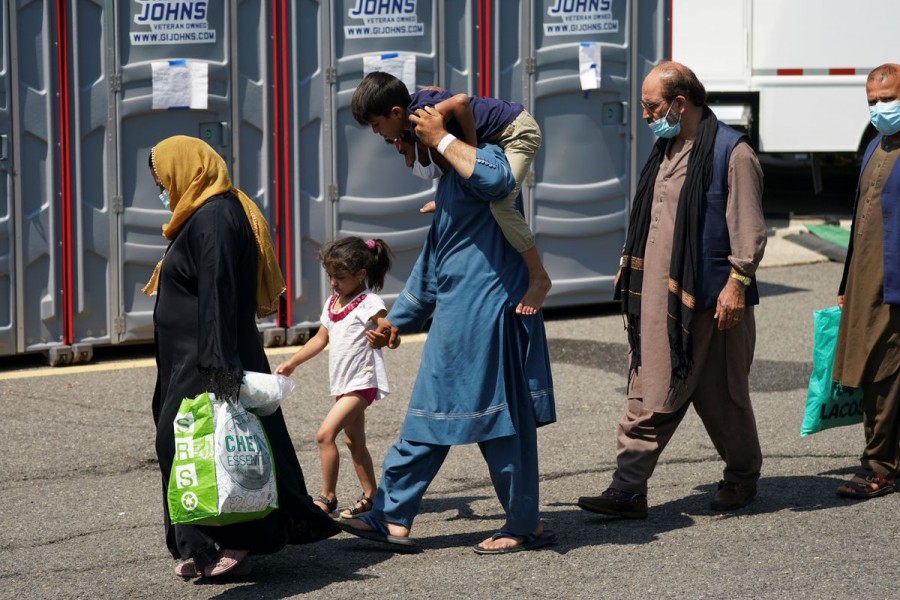 An Afghan man carries a boy on his shoulders upon arrival at a processing center for refugees evacuated from Afghanistan at the Dulles Expo Center near Dulles International Airport in Chantilly, Virginia, U.S., August 24, 2021. REUTERS/Kevin Lamarque