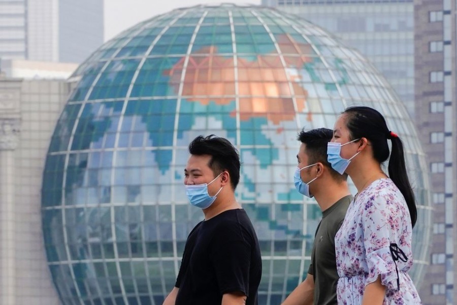 People wearing protective face masks walk along The Bund in front of the Lujiazui financial district of Pudong, following new cases of the coronavirus disease (COVID-19), in Shanghai, China August 25, 2021. REUTERS/Aly Song