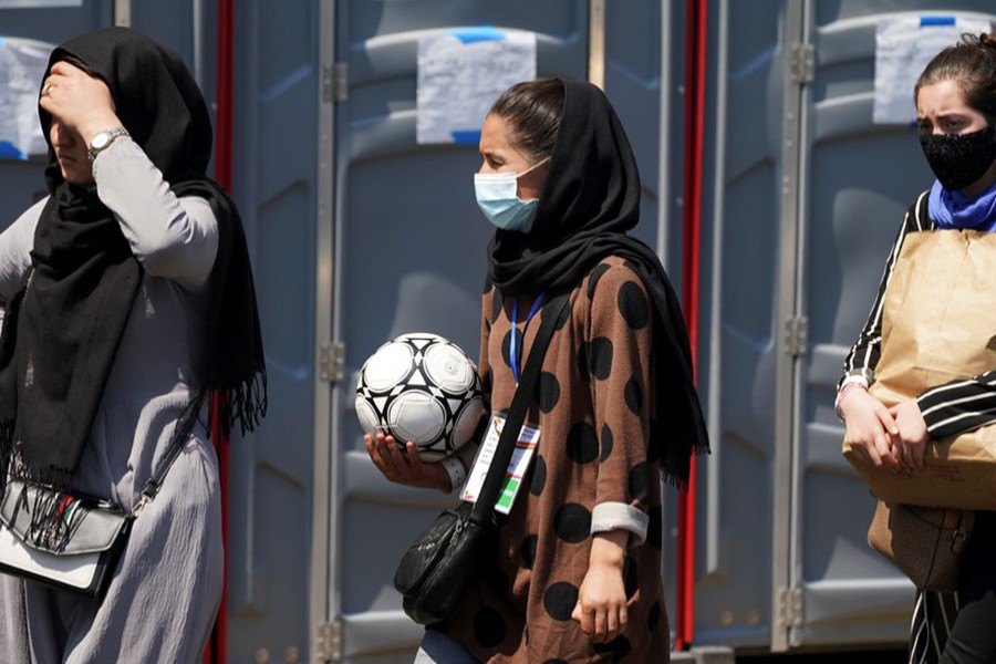 An Afghan woman holding a soccer ball and wearing a CAFA (Central Asian Football Association) credential, waits in line at a processing centre for refugees evacuated from Afghanistan at the Dulles Expo Center near Dulles International Airport in Chantilly, Virginia, US on August 24, 2021 — Reuters/Files