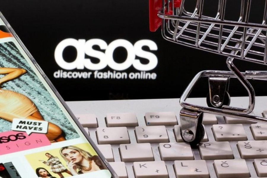 A smartphone with the ASOS app and a keyboard and shopping cart are seen in front of a displayed ASOS logo in this illustration picture taken October 13, 2020. REUTERS/Dado Ruvic