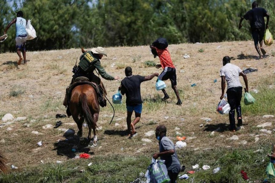 A US law enforcement officer on horseback chases migrants returning to the United States after buying food in Mexico, as seen from Ciudad Acuna, Mexico September 19, 2021. Reuters