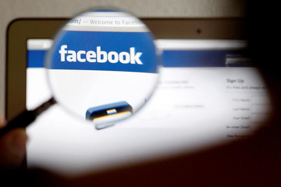 In this photo illustration, a Facebook logo on a computer screen is seen through a magnifying glass held by a woman in Bern on May 19, 2012 — Reuters/Files