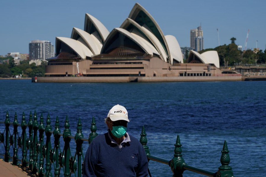 A person in protective face mask walks along the harbour waterfront across from the Sydney Opera House during a lockdown to curb the spread of coronavirus disease (Covid-19) outbreak in Sydney, Australia on October 6, 2021 — Reuters/Files