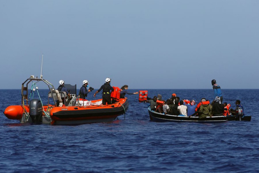Rigid-hulled inflatable boat (RHIB) crew members from the German NGO migrant rescue ship Sea-Watch 3 distribute life jackets to migrants in a small wooden boat in international waters off the coast of Libya, in the western Mediterranean Sea on August 1, 2021 — Reuters/Files
