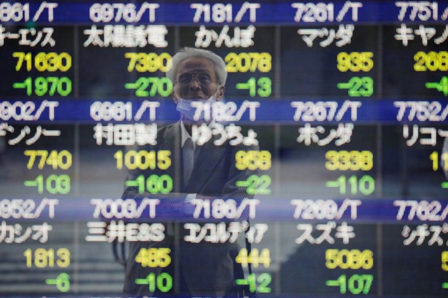 A man wearing a protective mask, amid the COVID-19 outbreak, is reflected on an electronic board displaying stock prices outside a brokerage in Tokyo, Japan, September 21, 2021. REUTERS/Kim Kyung-Hoon