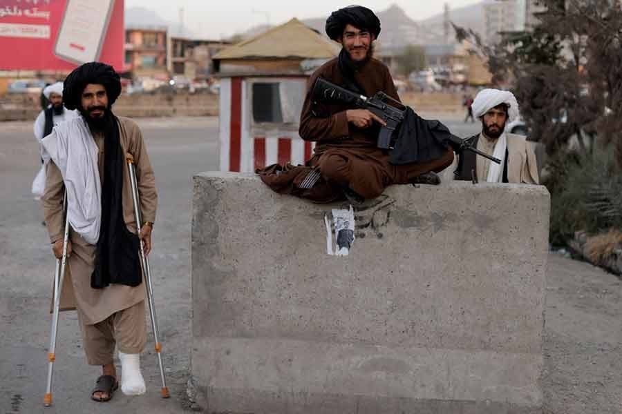 Taliban fighter Mira Jan Himmat, 30, and Rafiullah, 26, from Helmand province smiling while standing guard at a checkpoint in Kabul of Afghanistan on October 5 –Reuters file photo
