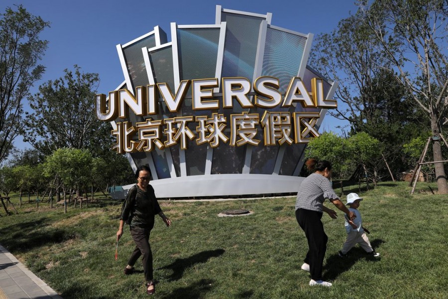 People walk past a giant sign of the Universal Beijing Resort ahead of its opening, in Beijing, China August 27, 2021. REUTERS/Tingshu Wang