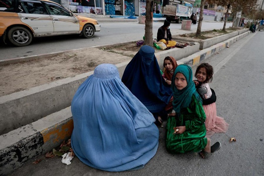 Women wearing burqas sit with their children as they beg along a road in Kabul, Afghanistan October 26, 2021. Reuters