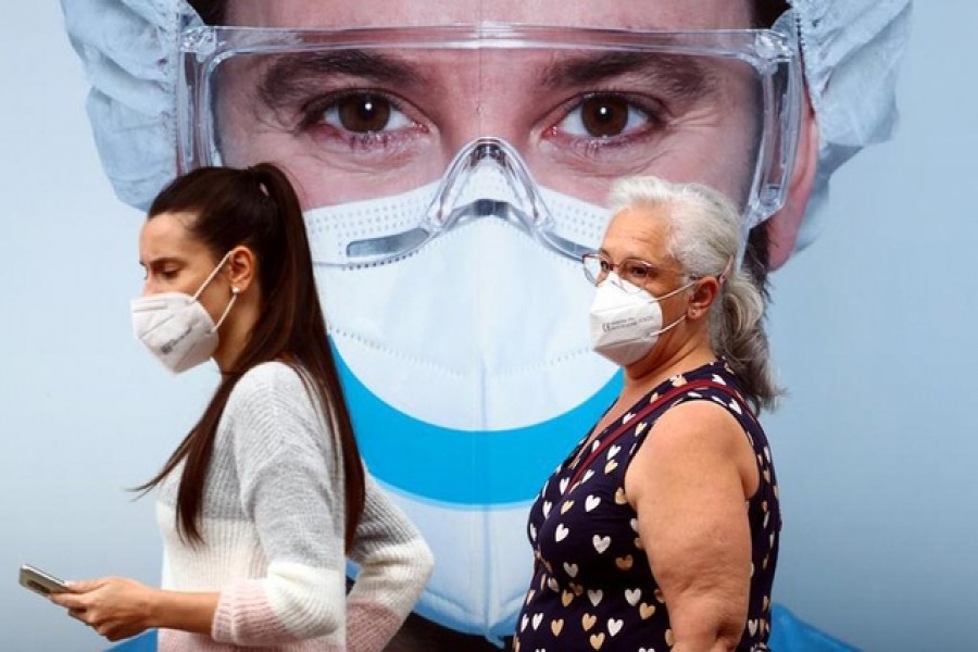 People, wearing protective face masks, walk past a dental clinic advertisement at Vallecas neighbourhood in Madrid, Spain, September 18, 2020. REUTERS/Sergio Perez