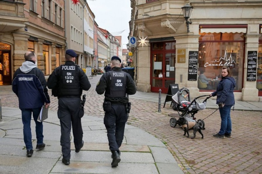 A member of the public order office is accompanied by police officers as he checks the coronavirus disease (COVID 19) "2G" protocol in Pirna, Germany, November 24, 2021. REUTERS/Matthias Rietschel
