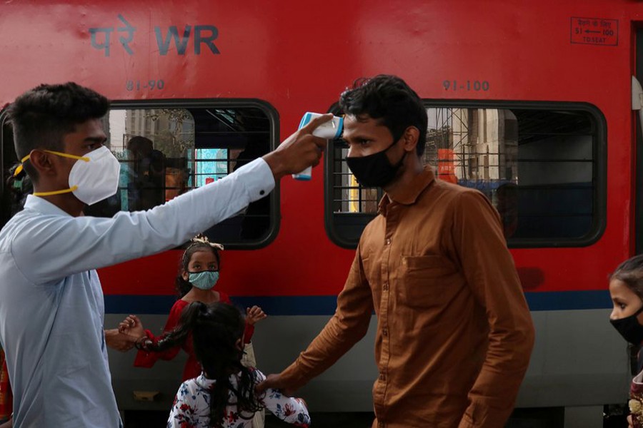 A healthcare worker checks the temperature of a passenger upon his arrival at a railway station, amidst the coronavirus disease (Covid-19) pandemic, in Mumbai, India on November 29, 2021 — Reuters photo