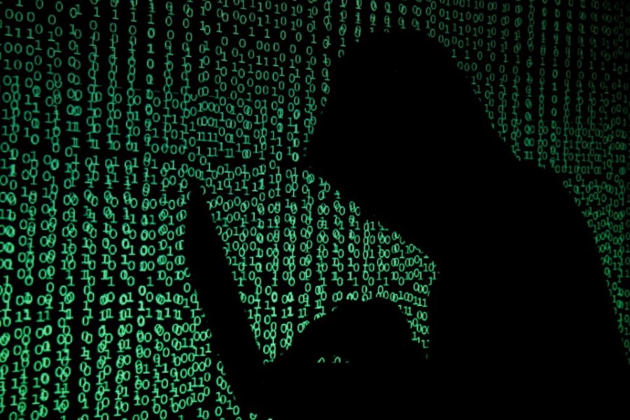 A hooded man holds a laptop computer as cyber code is projected on him in this illustration picture taken on May 13, 2017 — Reuters/Files