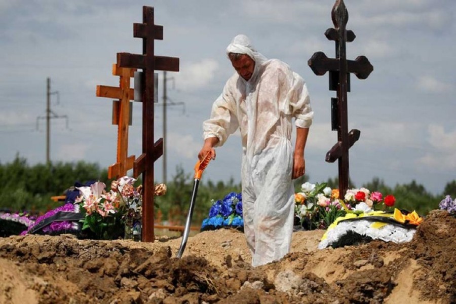 A grave digger wearing personal protective equipment (PPE) as a preventive measure against the coronavirus disease (COVID-19) buries a person at a graveyard on the outskirts of Saint Petersburg, Russia June 25, 2021. REUTERS/Anton Vaganov