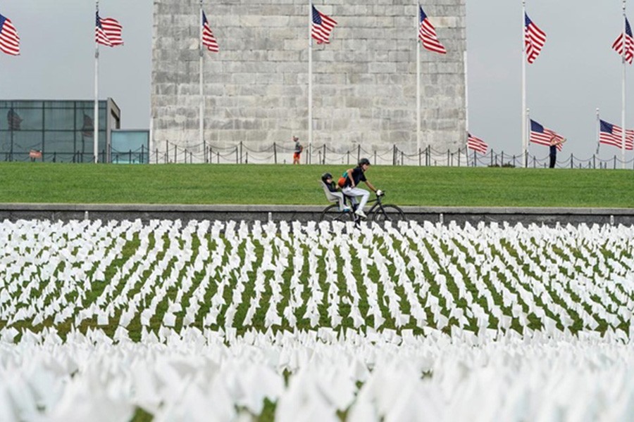 A cyclist rides past an exhibition of white flags representing Americans who have died of coronavirus disease (COVID-19), placed over 20 acres of the National Mall, in Washington, US, September 17, 2021. REUTERS/Joshua Roberts