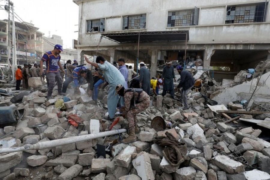 People and paramilitary personnel clear the rubble after a blast in an industrial area in Karachi, Pakistan December 18, 2021. REUTERS