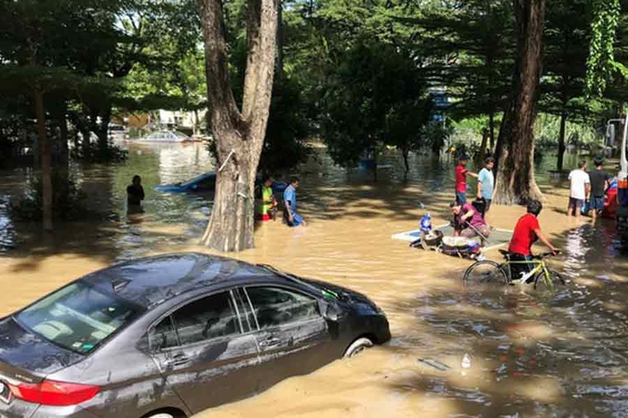 People wading among partially submerged vehicles through flood waters in Selangor state of Malaysia on Monday –Reuters photo