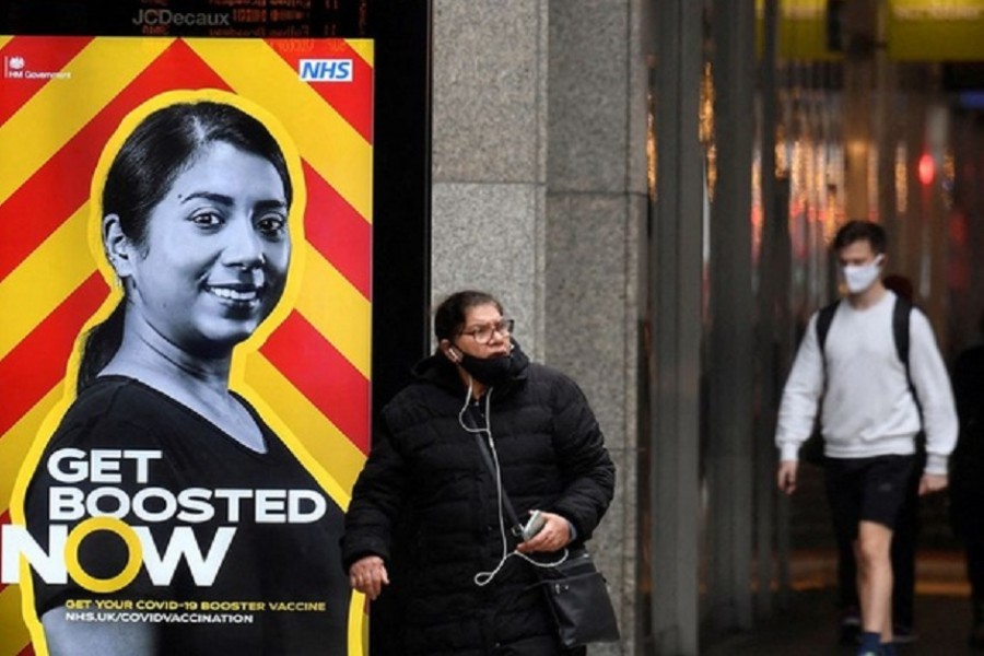 People walk past a government health campaign advertisement encouraging people to take a coronavirus disease (COVID-19) vaccine booster dose, at a bus stop, amid the spread of the COVID-19 pandemic, in London, Britain, December 17, 2021. REUTERS