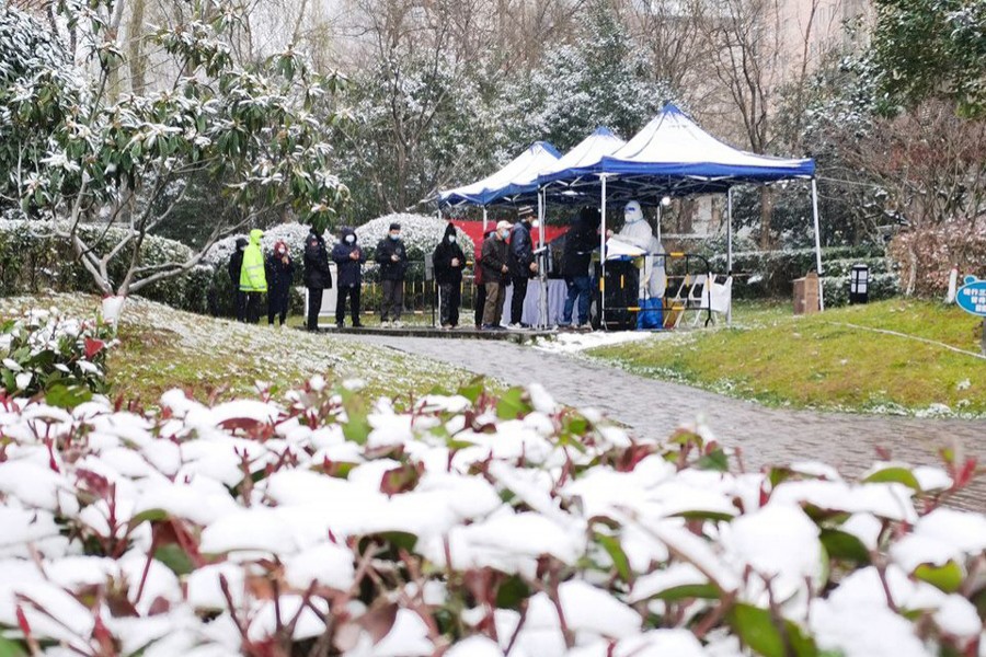 People line up in the snow for nucleic acid testing at a residential compound under lockdown following the coronavirus disease (Covid-19) outbreak in Yanta district of Xian, Shaanxi province, China on December 25, 2021 — cnsphoto via REUTERS