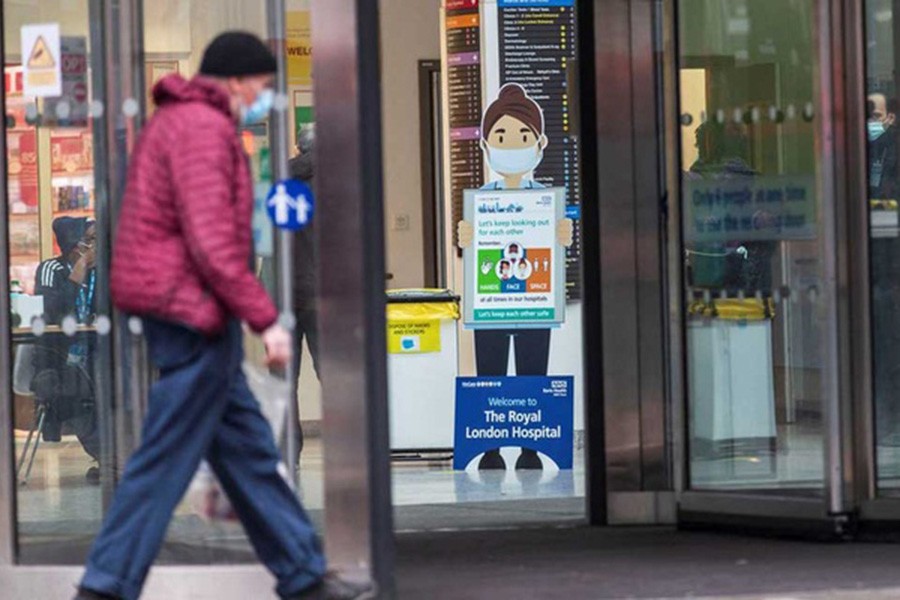 A man wearing a face mask, amid the spread of the coronavirus disease (COVID-19), walks past a COVID-19 advisory poster at the Royal London Hospital, in London, Britain December 31, 2021. REUTERS/May James