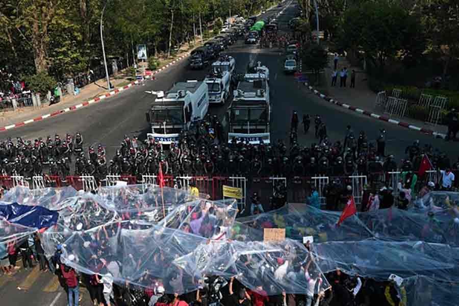 People cover with plastic in case of a water cannon during a rally against the military coup and to demand the release of elected leader Aung San Suu Kyi in Yangon on February 9 last year -Reuters file photo