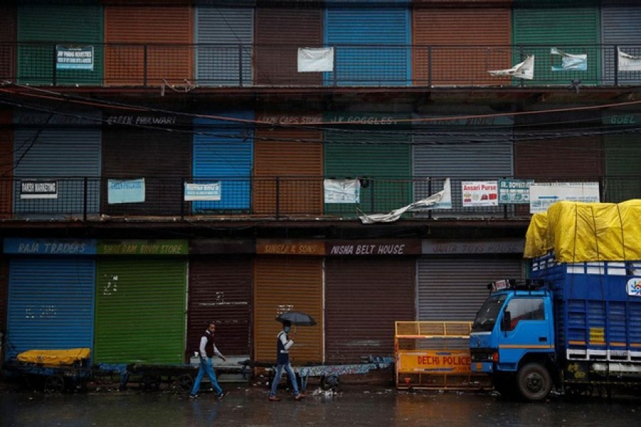 People walk past closed shops at a market area after authorities in the capital ordered a weekend curfew, following the rise in the coronavirus disease (Covid-19) cases, in the old quarters of Delhi, India, January 8, 2022 – Reuters/Adnan Abidi