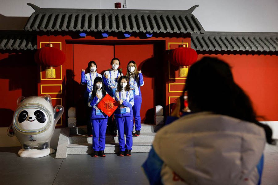 Volunteers pose for photo next to the installation of Bing Dwen Dwen and Shuey Rhon Rhon, mascots of the Beijing 2022 Winter Olympics and Paralympics, at the Main Press Centre ahead of the Beijing 2022 Winter Olympics, in Beijing, China January 26, 2022 – Reuters/Tyrone Siu