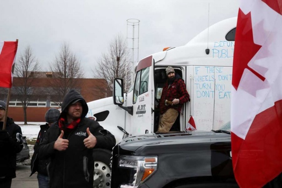 A protestor gestures as the Ambassador Bridge, which connects Detroit and Windsor, stands effectively shut down after truckers and their supporters blocked it in protest against coronavirus disease (COVID-19) vaccine mandates, in Windsor, Ontario, Canada February 10, 2022 – Reuters